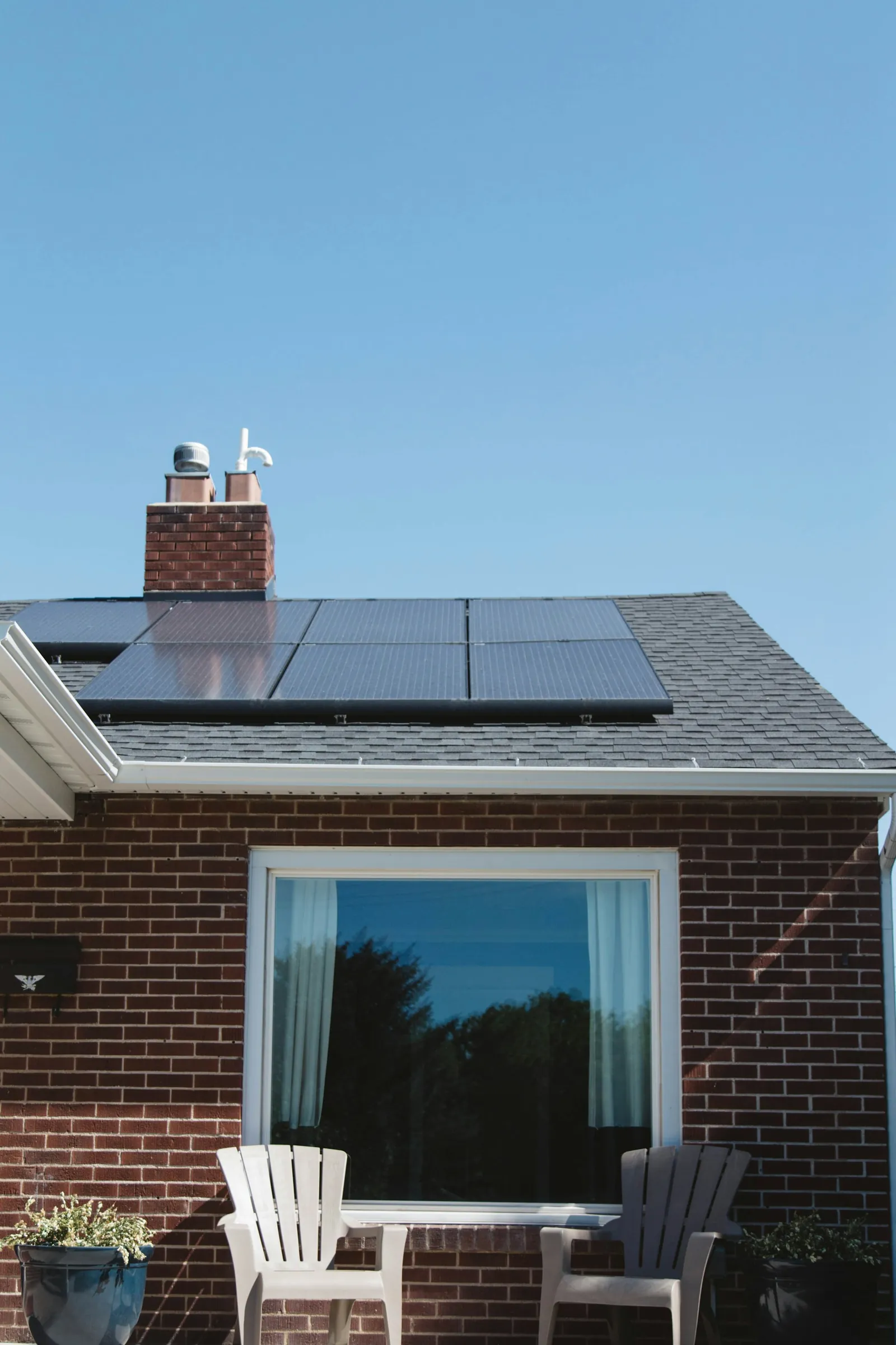 Solar panels on the roof of a brick house in Virginia, above a wide front window