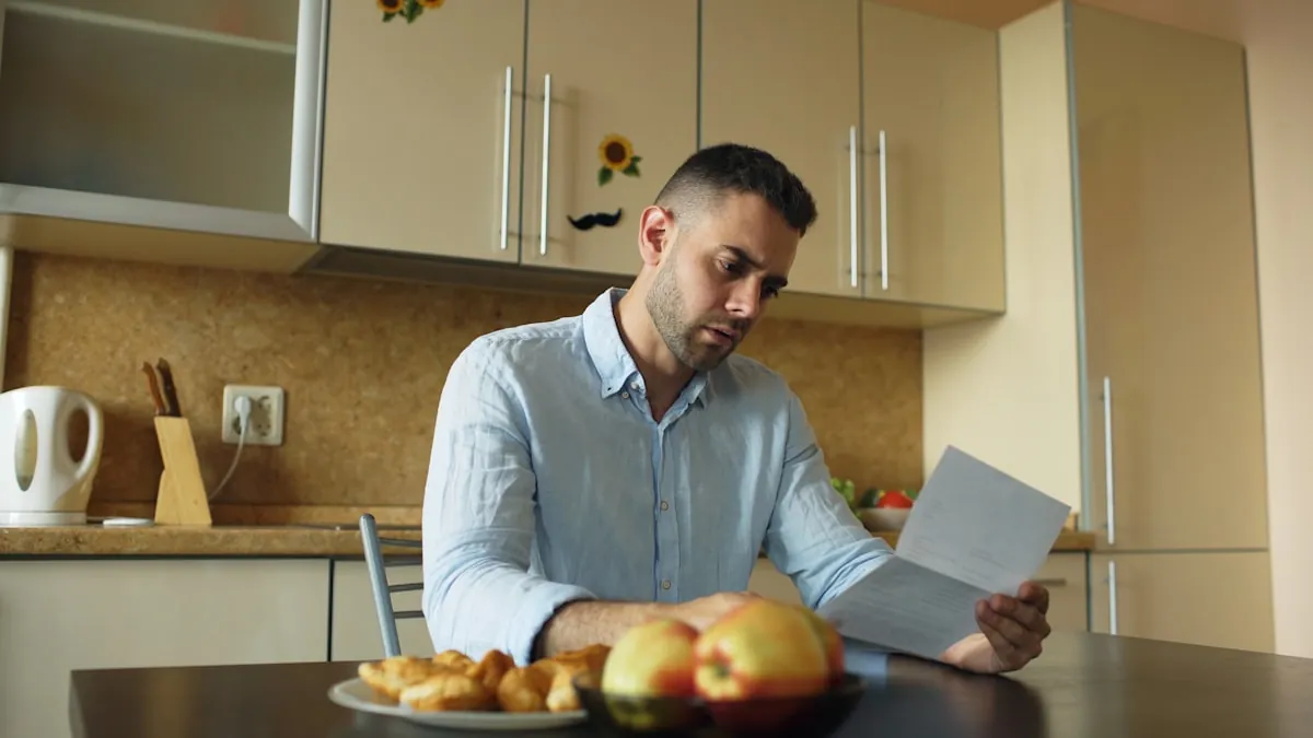 A man at his kitchen table reading his electric bill